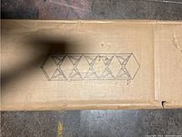 Illustration of assembled bookshelf showing five levels and cross braces on side supports. Box top view with printed image of shelf.