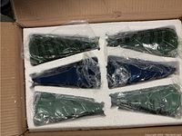 Sealed ceramic fig trees in foam packaging inside shipping box, showing six wrapped tree decorations.