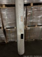 Full view of rolled mattress in plastic wrap against stacked pallets