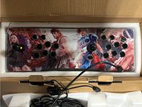 Top view photo of the arcade controller panel showing colorful artwork of classic fighting game characters and placement of buttons and joysticks for two players.
