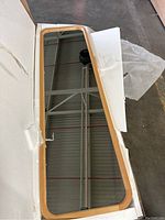 Full-length standing mirror with a smooth solid wood frame seen inside open box with protective packaging.