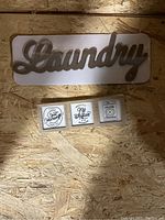 Wooden 'Laundry' wall sign and three-piece wall plaque art held against a wooden textured background
