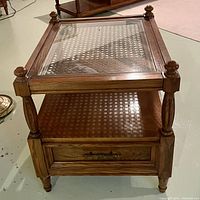 Wooden coffee table with glass top and cane insert showing drawer and turned legs