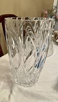 Clear crystal vase with a carved swirl pattern on a table.