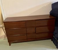 Wooden dresser with six drawers, clean finish, rectangular shape with integrated recessed handles.