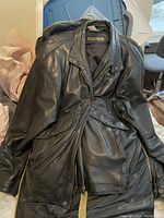 Black leather men's coat by Danier laid out with zipper and snap button details visible.