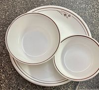 Corelle plates and bowls stacked, showing brown rims and floral pattern
