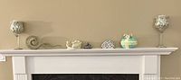 Wide shot of mantel showing all seven decorative ornaments including mosaic candle holders, silver candle holders, figurines and Easter egg-shaped ornament.