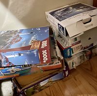 Photo of a stack of seven puzzle boxes showing puzzle images and piece counts