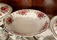 Large bowl with floral rose pattern and scalloped edges with gold trim.