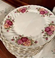 Stack of 12 side plates with floral Rose Garden design, gold trim on scalloped white ironstone.