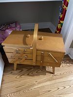 Closed wooden multi-tier cantilever sewing box showing its construction, handle, and finish.