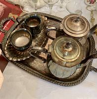 Silver tea and coffee set on tray including teapot, coffee pot, and creamer showing overall condition and style.