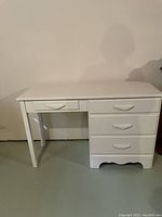 Front view of the small white wooden desk showing the drawers and desk surface.