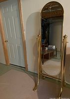 Full-length standing mirror with brass or gold-tone metal frame and swivel function