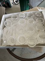 40 clear crackle glass votive candle holders arranged in a box, showing their round shape and clear glass material.