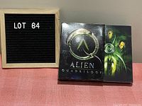 Front view of Alien Quadrilogy DVD set box and slipcase showing embossed alien design and title.
