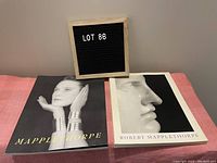 Two Robert Mapplethorpe art books displayed side by side, one with a woman's portrait on the cover, the other with a close-up profile photo.