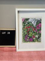 Frontal view of framed floral still life photo showing flowers and white frame