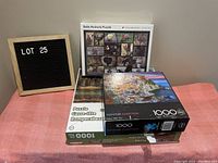 Lot includes three 1000-piece jigsaw puzzles stacked, one unopened with baby animals image, others show scenic landscapes.
