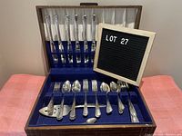 Full view of vintage silver plate cutlery set in original case, displaying knives, forks, spoons and serving pieces inside a blue velvet lined case with cream satin lid lining.