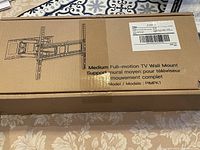 Box showing the TV wall mount schematic and model description with label and shipping details attached.