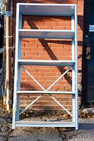 Front view of the light blue metallic shelving stand showing four shelves and the braced support structure on the bottom half.