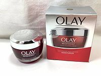 Jar of Olay Regenerist Micro-Sculpting Cream with silver lid and red translucent container beside its box showing branding and product details.