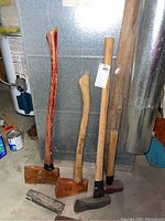 Full view of the axes, maul, and wedges arranged on a concrete floor in a workshop setting.