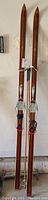 Full view of the pair of wooden Bonna Alpine Skis model 2400 with bindings and attached straps.