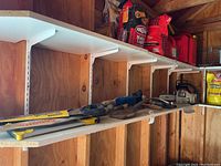 Full view of shed shelf showing chainsaw at right and assorted tools left