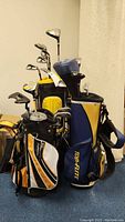 Photo showing three sets of kids' golf clubs with bags in a room.