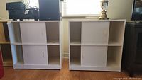 Photo of two white cabinets side by side with sliding doors and open shelving, showing full view from front