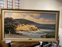 Full view of the wood framed oil painting print on board showing coastal landscape with trees, cliffs and ocean.