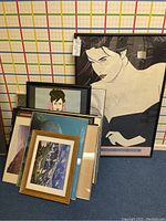 Group photo showing all framed posters and prints stacked together, including the prominent large black frame with stylized woman art.