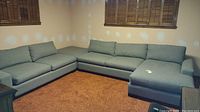 Corner view of grey upholstered sectional sofa with chaise in basement room