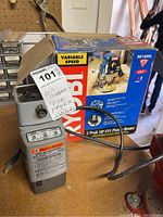 Black & Decker drill bit sharpener next to boxed Ryobi plunge router on wood shop bench with a MaxSold tag labeled '101'.
