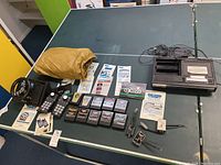 Overview of ColecoVision system components, controllers, steering wheel, game cartridges, manuals, and splitters arranged on table.