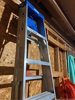 Side view of one Werner aluminum extension ladder leaning against a wall in a wooden framed room