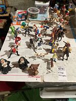 Photo of action figures including knights, nuns, monks, cowboys, mounted on horses and standing, alongside repair supplies.