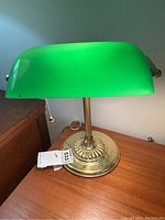 Front view of bank teller lamp showing green glass shade, brass base, and pull chain