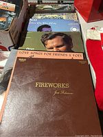 Photo showing several vinyl record albums stacked side by side, including visible covers of José Feliciano's 'Fireworks', an album titled 'Love Songs For Friends & Foes', and a Taco album titled 'After The Rain'