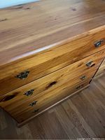 Top angled view of a wooden dresser showing four drawers with metal handles and wood grain.