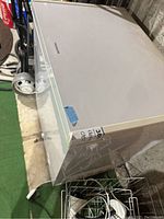 Closed view of the white Frigidaire chest freezer with visible logo on the top and blue tape on the corner.