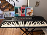 Full view of Casio CT-638 keyboard on stand with three manuals behind it on top of keyboard.