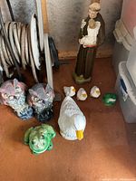 Full assortment of lawn ornaments including Saint Francis statue, white geese, frogs, and owls.