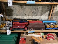 Full shelf view of various Lionel model train cars including tanks, gondolas, and boxcars.