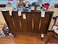Full shot of the mid century modern wooden buffet table showing wood grain, decorative front panel, and tapered legs. Small scratches and scuff marks visible on surface.