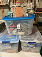 Three large plastic storage bins stacked, showing partial contents of medieval castle playset pieces inside the translucent bins.