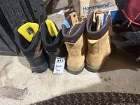 Back view of two pairs of men's boots, one tan and one dark brown, standing side by side showing heels and collar padding.